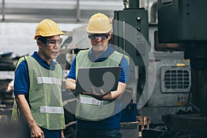 Mechanic and staff engineer talking nearby a machine in a big factory