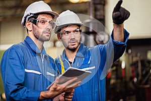 Mechanic and staff engineer talking nearby a machine in a big factory about latest new planing, Two men engineer talking in modern