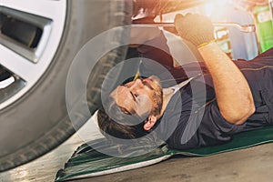 Mechanic staff worker working under car fix and repair tire suspension in garage