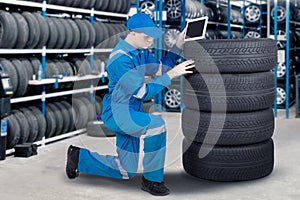 Mechanic with tablet computer checking tyre