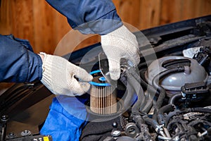 A mechanic takes out an old, dirty fuel filter after refueling with low-quality fuel. Car maintenance, close-up