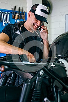 Mechanic talking phone while fixing motorbike