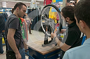 Mechanic teaching people how to true a bike wheel on a truing stand