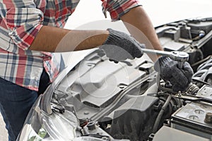 Mechanic, technician man check the car engine in garage. Car service, repair, fixing, checking maintenance working with socket