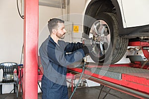 Mechanic Tightening Nuts On Tire With Impact Wrench