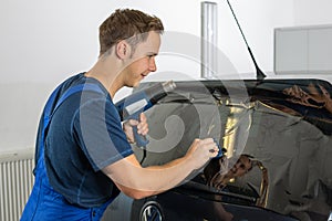 Mechanic tinting car window with tinted foil or film photo