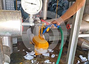 A mechanic to defrost the ice by water spray attached to the compressor in the chiller system