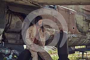 Mechanic in uniform and flight helmet carries out maintenance of an old military bomber in an open-air museum.
