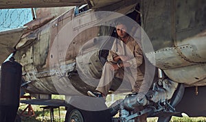 Mechanic in uniform and flight helmet carries out maintenance of an old military bomber in an open-air museum.