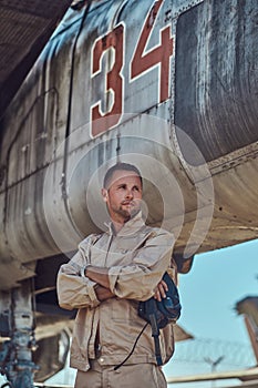 Mechanic in uniform standing near a war fighter-interceptor in an open-air museum.