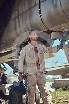 Mechanic in uniform standing near a war fighter-interceptor in an open-air museum.