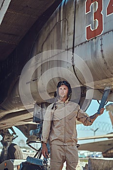 Mechanic in uniform standing near a war fighter-interceptor in an open-air museum.