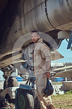 Mechanic in uniform standing near a war fighter-interceptor in an open-air museum.