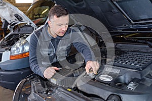 Mechanic unscrewing oil tank in auto repair