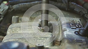 A mechanic unscrews the spark plugs on a car engine.