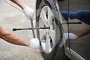 mechanic uses a cross wrench to tighten the wheel nuts.concept of wearing white gloves
