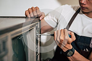 The mechanic uses a screwdriver to tighten the screws on the TV