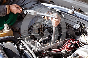 the mechanic uses a torque dynamometer wrench to install the cylinder head at old engine. Disassembled carburetor motor