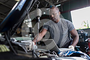 Mechanic using compute for Diagnostic  machine tools ready to be used with car. Car mechanic using a computer laptop to diagnosing