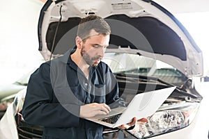 Mechanic Using Computer Diagnostic Program While Repairing Car