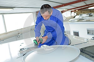 Mechanic using cordless drill on roof camper van