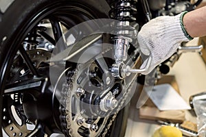 Mechanic using Hex Key Wrench or L wrench tool working on motorcycle at motorbike garage , concept of motorcycle maintenance and