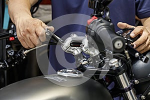 Mechanic using Hex Key Wrench working on motorcycle at motorbike garage , concept of motorcycle maintenance and repair . selective photo