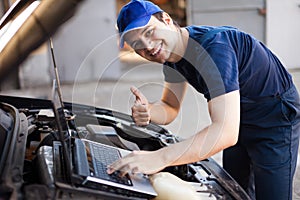 Mechanic using a laptop computer to check a car engine