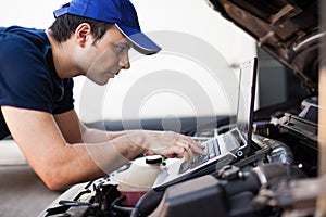 Mechanic using a laptop computer to check a car engine