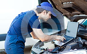 Mechanic using a laptop computer to check a car engine