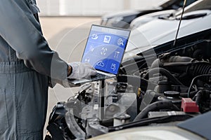 Mechanic using a laptop computer to check collect information during work a car engine. service maintenance of industrial to