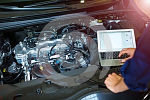 Mechanic Using Laptop While Examining Car Engine