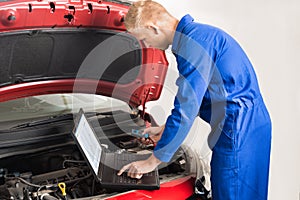 Mechanic Using Laptop While Repairing Car