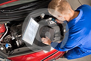 Mechanic Using Laptop To Repair Car