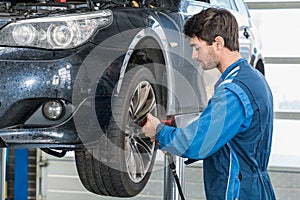 Mechanic Using Pneumatic Wrench To Fix Car Tire