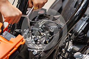 Mechanic using a wrench and socket on the engine of a motorcycle , selective focus .