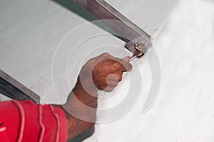 The mechanic is using a wrench to tighten the nuts on the wall of the house.