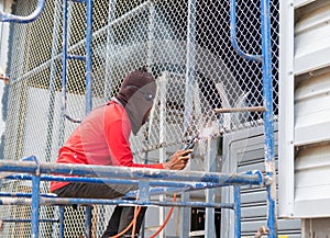 A mechanic is welding a steel net on the garage door