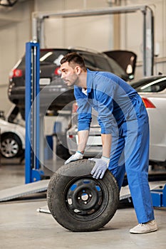 Mechanic with wheel tire at car workshop