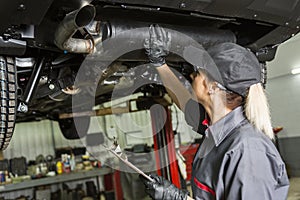 Mechanic woman working on car in his shop