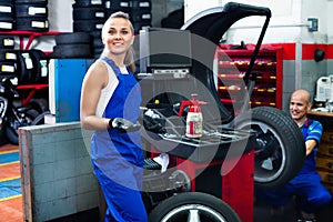 Mechanic woman working on new tire fitting in service point