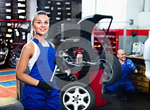 Mechanic woman working on new tire fitting in service point