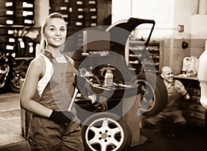 Mechanic woman working on new tire fitting in service point