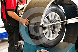 Mechanic worker makes computer wheel balancing on special equipment machine tool in auto repair service