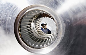 Mechanic, worker seen through a giant gear axle