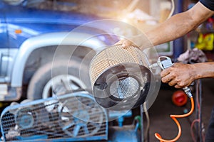 A mechanic working in an auto repair shop Blow the car air filter to clean the dust in the car air filter in your garage or car