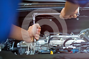 Mechanic working on car engine in auto repair shop