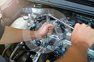 Mechanic working on car engine in auto repair shop