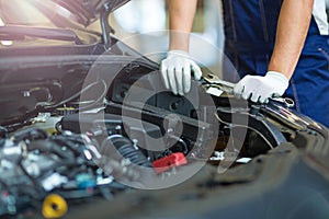 Mechanic working on car engine in auto repair shop