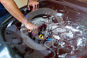 Mechanic working on car engine in auto repair shop